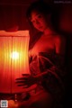 A woman in a kimono sitting next to a lamp.