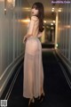 A woman in a sheer dress standing in a hallway.