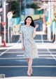 A woman in a blue dress is walking down the street.