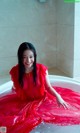 A woman in a red dress sitting in a bathtub.