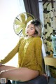 A woman sitting on top of a chair next to a fan.