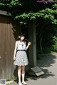 A young woman standing in front of a wooden fence.