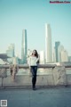 A woman standing on a bridge in front of a city skyline.