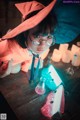 A little girl in a witches hat and glasses sitting at a table.