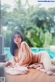 A woman in a pink robe laying on a bed next to a pool.