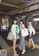 A group of three women standing next to each other at a train station.