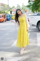 A woman in a yellow dress is standing on the street.