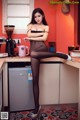 A woman in a black lingerie sitting on a kitchen counter.