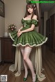 A woman in a green dress and white stockings posing for a picture.