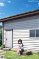 A girl sitting on a bench in front of a house.