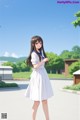 A girl in a white dress standing in a parking lot.