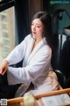 A woman in a white robe sitting on a chair.